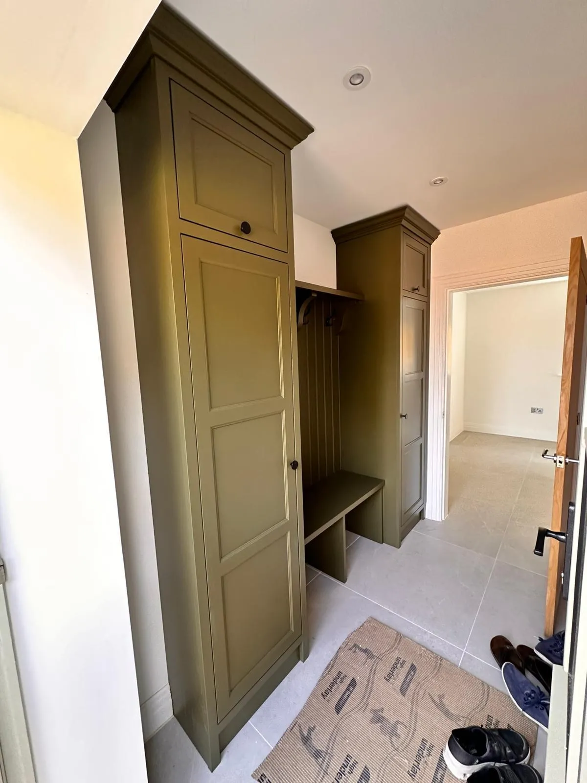 A hallway with a green cabinet and a pair of shoes on the floor.